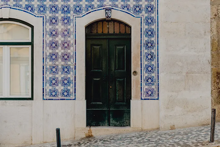 Husfasad klädd i blå azulejos med en mörkgrön ytterdörr